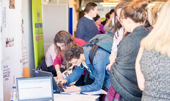 Students using a laptop at a busy recruitment fair,  campus, Edinburgh