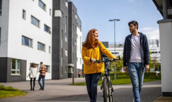 A  student with a bike talking to a fellow student on campus, Edinburgh