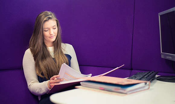 A  student reading over their work against a purple wall