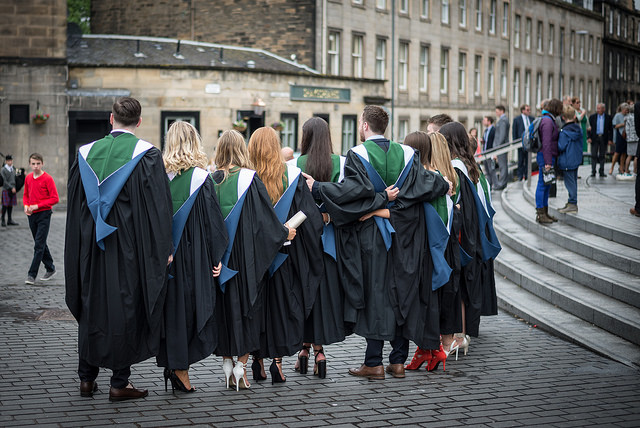 A row of  graduands standing in a row wearing their gowns outside Usher Hall