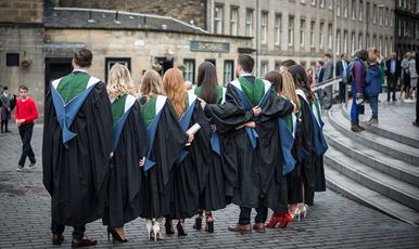 A row of  graduands standing in a row wearing their gowns outside Usher Hall