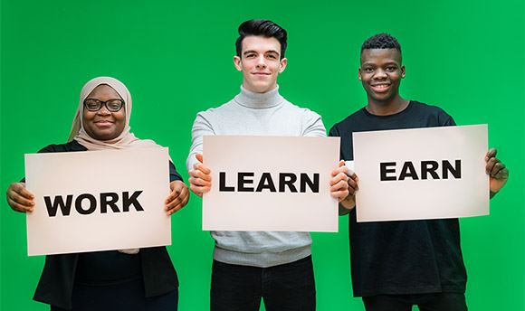 Three  students holding signs with the words "Work", "Learn" and "Earn"