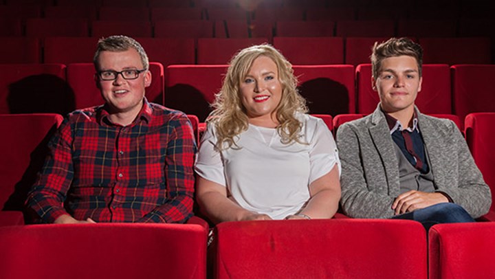 Three  students sitting in plush red seats at the theatre