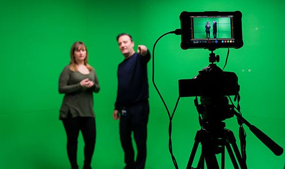 A  student being briefed in front of a green screen